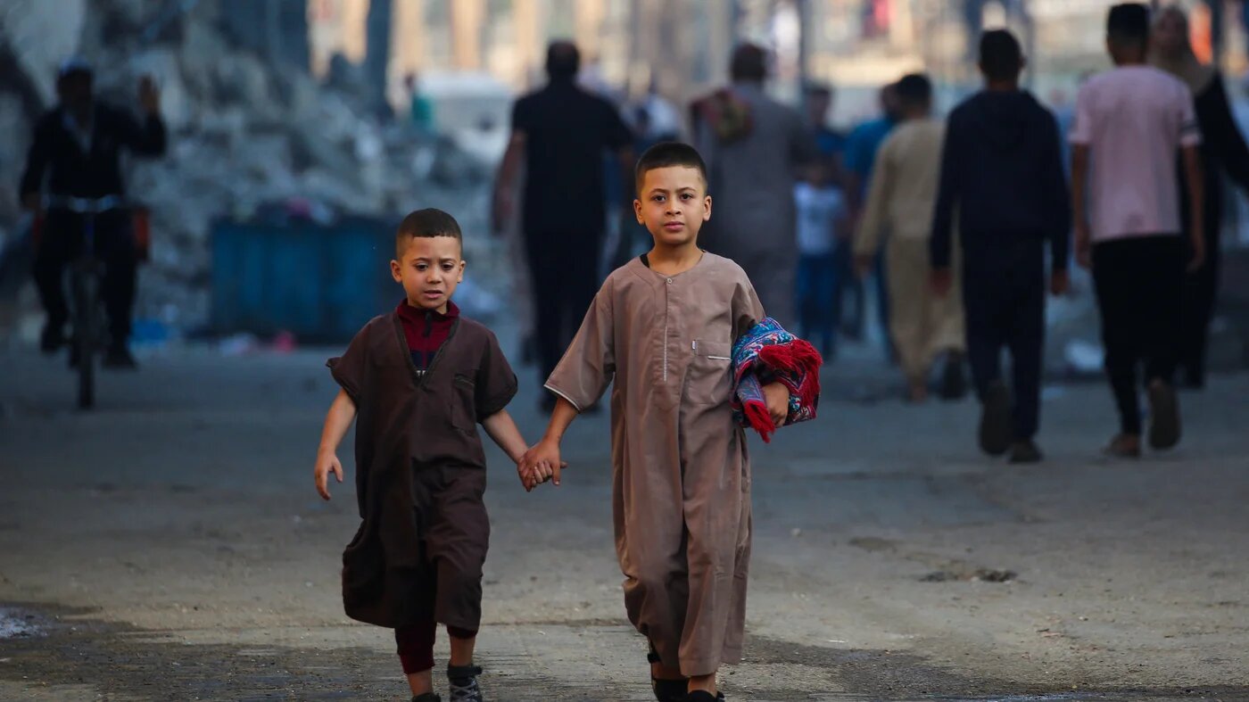 Two Palestinian children following morning prayer on the first day of Eid al-Adha in Nuseirat, central Gaza Strip, on 6 June, 2025, (AFP/Eyad Baba)
