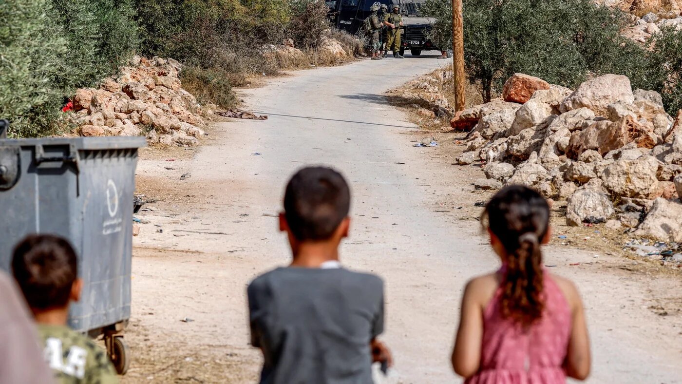 Children watch as Israeli security forces deploy nearby in the Palestinian village of al-Mughayyir, near Ramallah in the Israeli-occupied West Bank, on 29 September 2026 (AFP)
