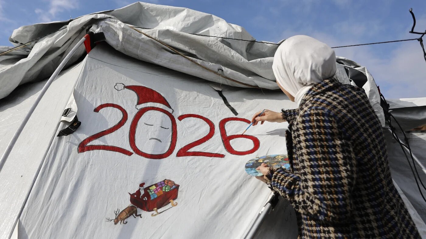 Sarah Saada, a 15-year-old displaced Palestinian, paints '2026' on her tent in Gaza City on 30 December 2025 (Omar al-Qattaa/AFP)