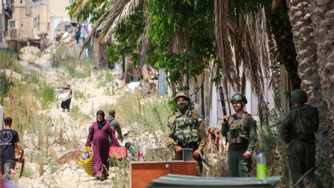 Palestinians collect their possessions as Israeli forces stand nearby in the Tulkarm refugee camp, northern occupied West Bank, 17 June 2026 (Mojahid Nawahda/MEE)