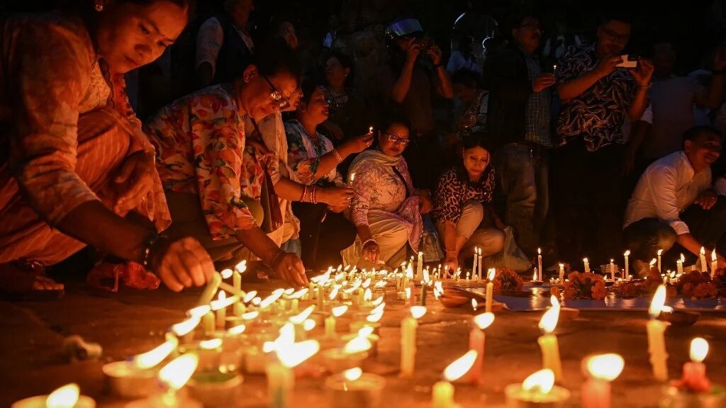 People light candles on the national day of mourning in Kathmandu on 7 September to remember the thousands of Nepalis killed in the August flash floods (Prakash Mathema/AFP)