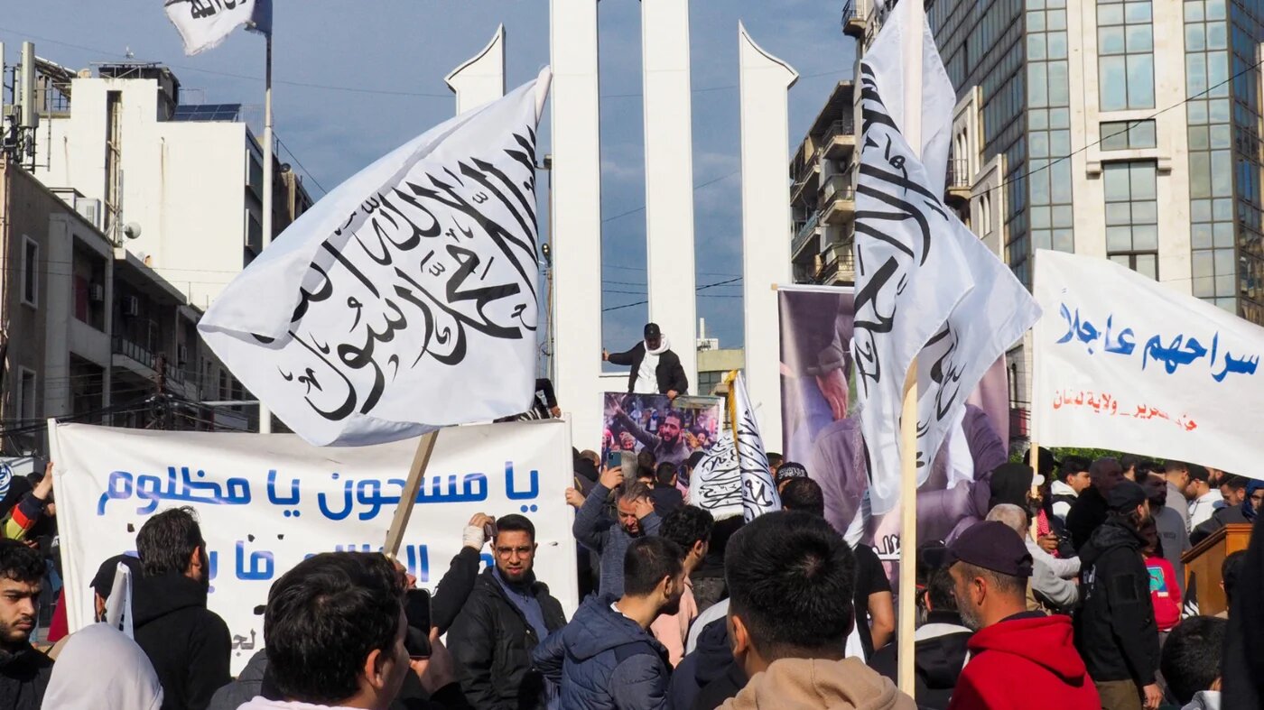 People wave flags during a protest calling for the release of detained Islamists held in Roumieh prison in the northern Lebanese port city of Tripoli on 5 January 2025 (Ibrahim Chalhoub/AFP)
