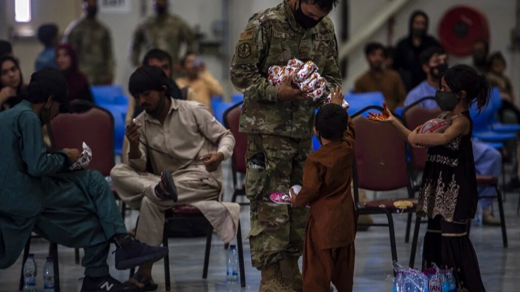 A US soldier distributes food to Afghan citizens on 16 August 2021, at Al Udeid Air Base, Qatar.