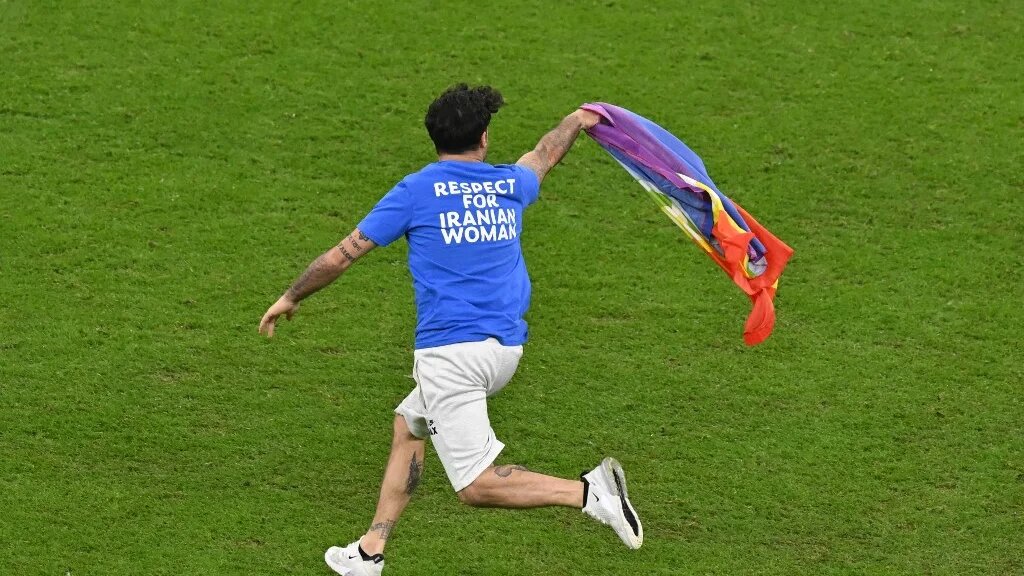 Un homme envahit le terrain tenant un drapeau LGBTQI+ lors du match de football du groupe H entre le Portugal et l’Uruguay au stade Lusail, au nord de Doha, le 28 novembre 2022 (AFP/Glyn Kirk)