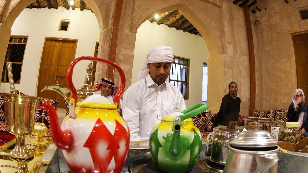 Un homme sert du gahwa traditionnel, préparé en torréfiant des grains de café puis en les faisant bouillir avec de la cardamome et du safran, à la maison culturelle Embrace Doha dans le souk Al-Wakrah, au sud de la capitale Doha, le 13 septembre 2022 (AFP/Karim Jaafar)