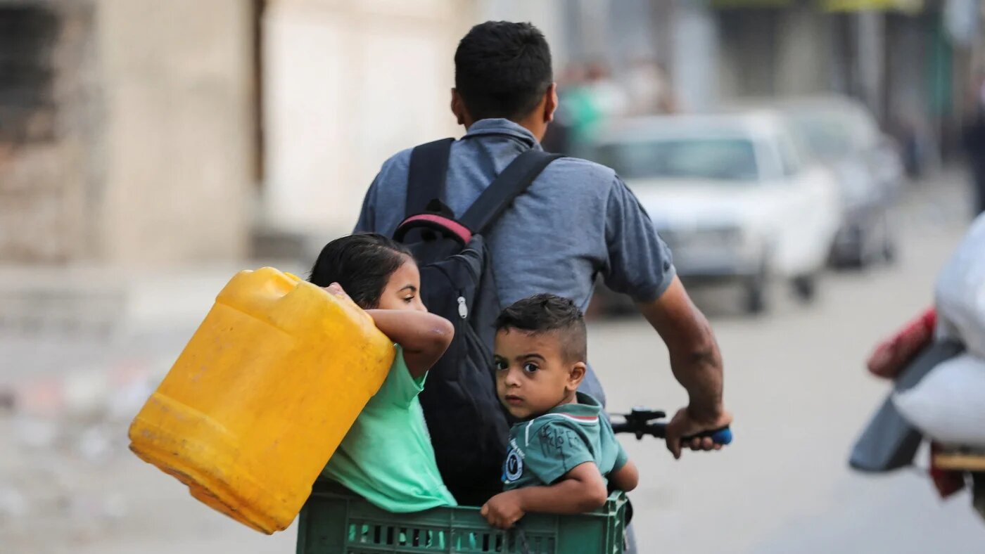 A Palestinian rides a bicycle with children along with their belongings as they flee Rafah on 28 May (Reuters/Hatem Khaled)