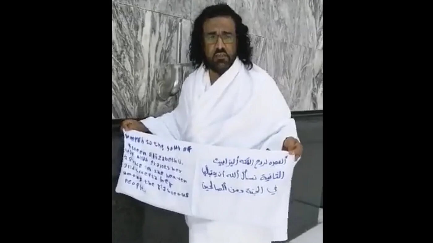 A screengrab from a social media video showing a Yemeni national in Mecca holding a banner that reads: “Umrah for the soul of Queen Elizabeth II, we ask Allah to accept her in heaven and among the righteous." 
