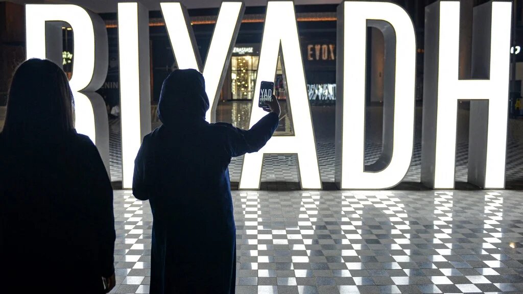 A woman uses her phone to take a picture of a lit "I LOVE RIYADH" sign at a shopping centre in Saudi Arabia's capital Riyadh on 31 October 2020 (AFP)