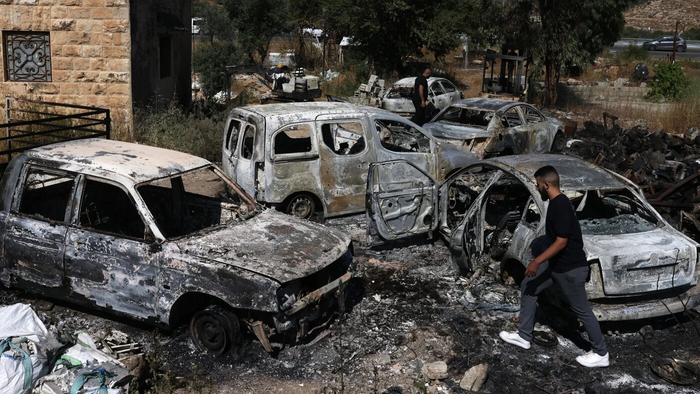 A man walks amid burnt cars, which were set ablaze by Israeli settlers, in the area of al-Lubban ash-Sharqiya in the occupied West Bank on 21 June 2023 (Ahmad Gharabli/AFP)