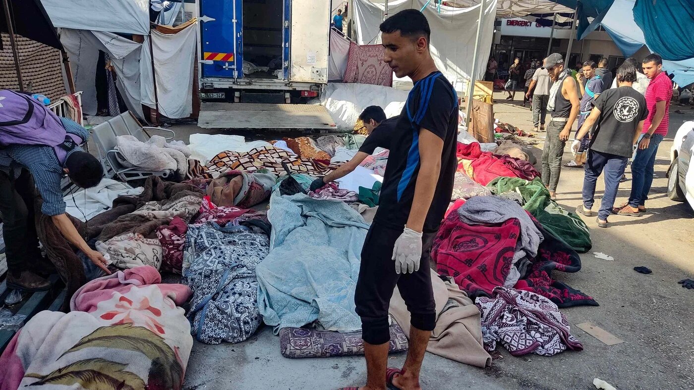 Men at al-Shifa hospital inspect bodies left outside in its courtyard on 10 November (AFP)