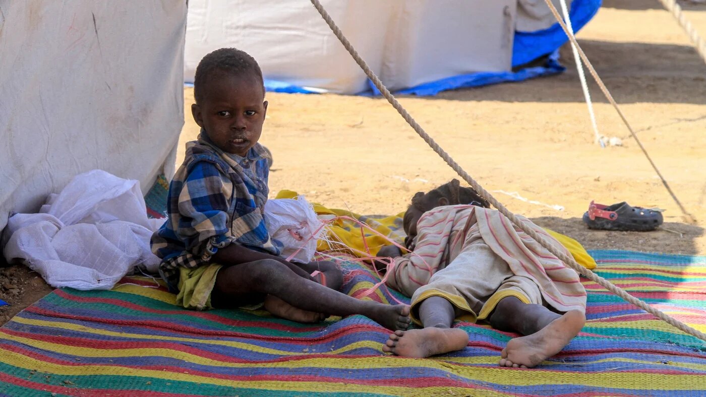 Children from el-Fasher rest outside their tent at a camp for displaced Sudanese people in the northern town of al-Dabba on 13 November 2025 (AFP)