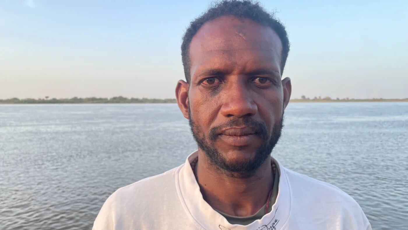 Al-Amin Idriss Mohammed, a commander of al-Tekeina's armed force, stands beside the Blue Nile (Daniel Hilton/MEE)