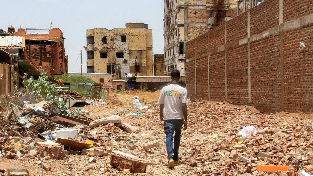 A man walks through rubble near heavily damaged buildings on the southwestern outskirts of Sudan’s capital Khartoum, on 30 July 2025 (Ebrahim Hamid/AFP)