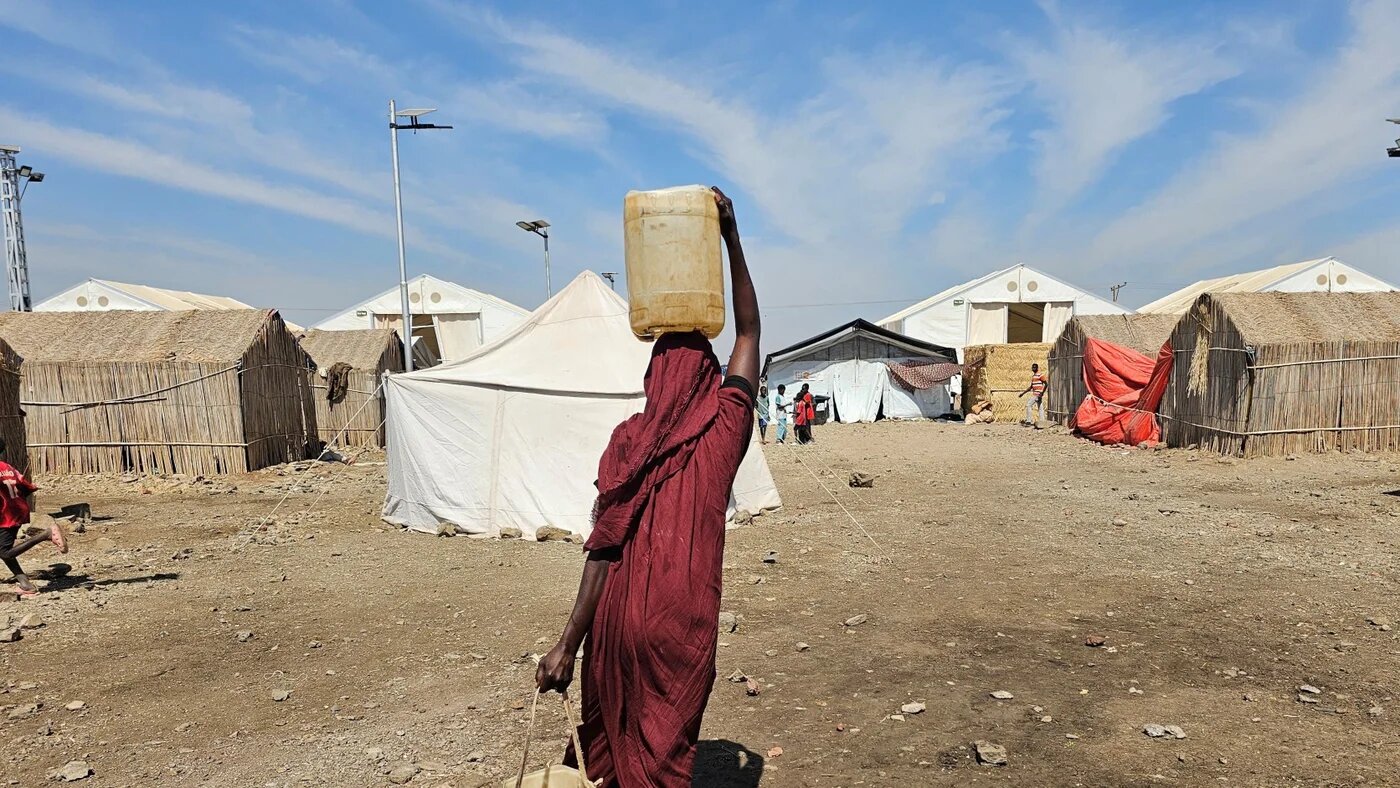 A Sudanese woman carries water at the Abu al-Naga displacement camp in Gedaref State, 420km east of the capital Khartoum on 6 February 2026 (AFP)