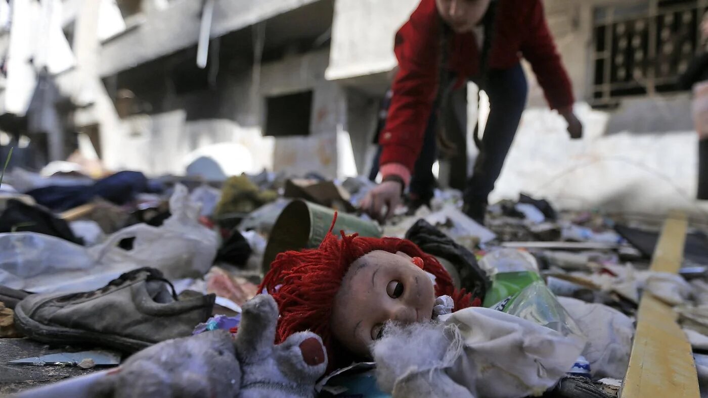 Une jeune fille fouille dans des affaires abandonnées dans les décombres des rues du camp palestinien de Yarmouk, dans la banlieue sud de la capitale syrienne Damas, le 25 novembre 2020 (AFP)