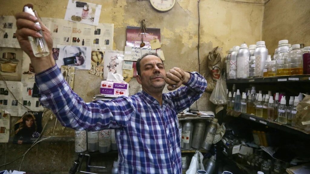 Le parfumeur syrien Mohammad al-Masri vaporise l’une de ses créations dans sa boutique, dans la vieille ville de Damas, le 31 octobre 2022 (AFP/Louai Beshara)
