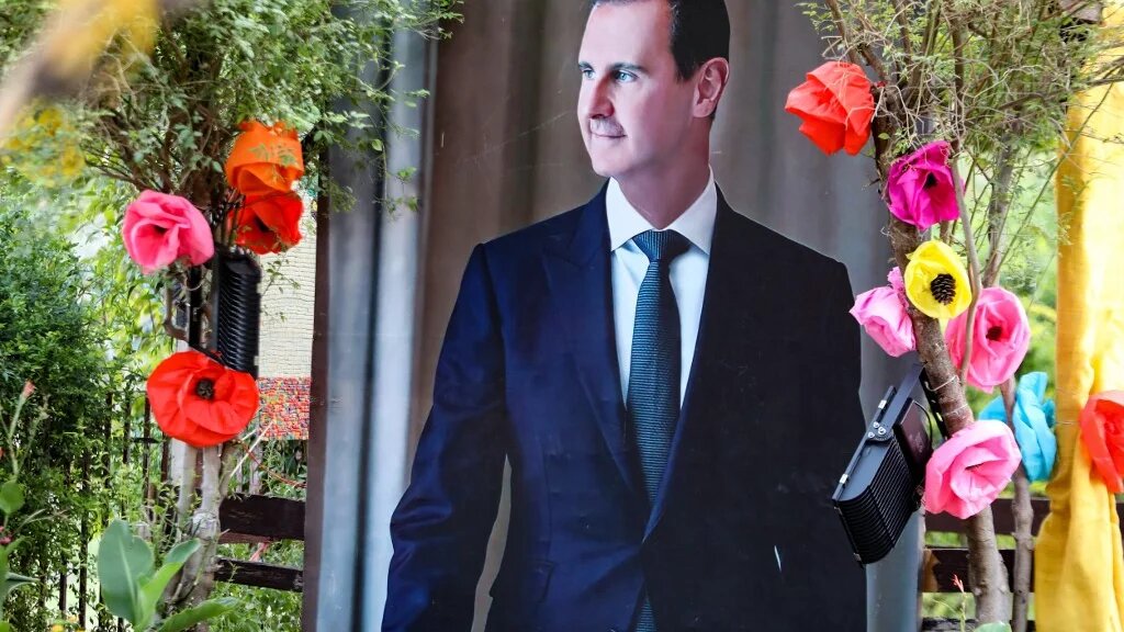 Un poster de Bachar al-Assad décoré avec des fleurs en papier, à Damas, le 22 juin 2022 (AFP/Louai Beshara)