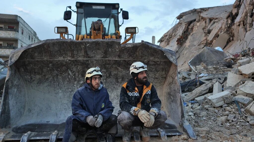 Des Casques blancs syriens sont assis sur une excavatrice, le 6 février 2023, dans la ville de Sarmada, dans la province d’Idleb, tenue par les rebelles (AFP/Aaref Watad)