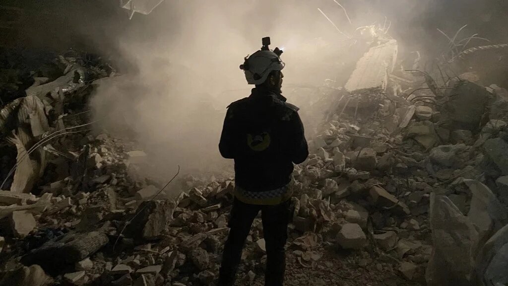 Un membre des Casques blancs se tient devant les décombres d’un immeuble lors de la recherche de survivants dans la ville syrienne tenue par les forces antigouvernementales de Jaindairis, le 8 février 2023 (AFP)