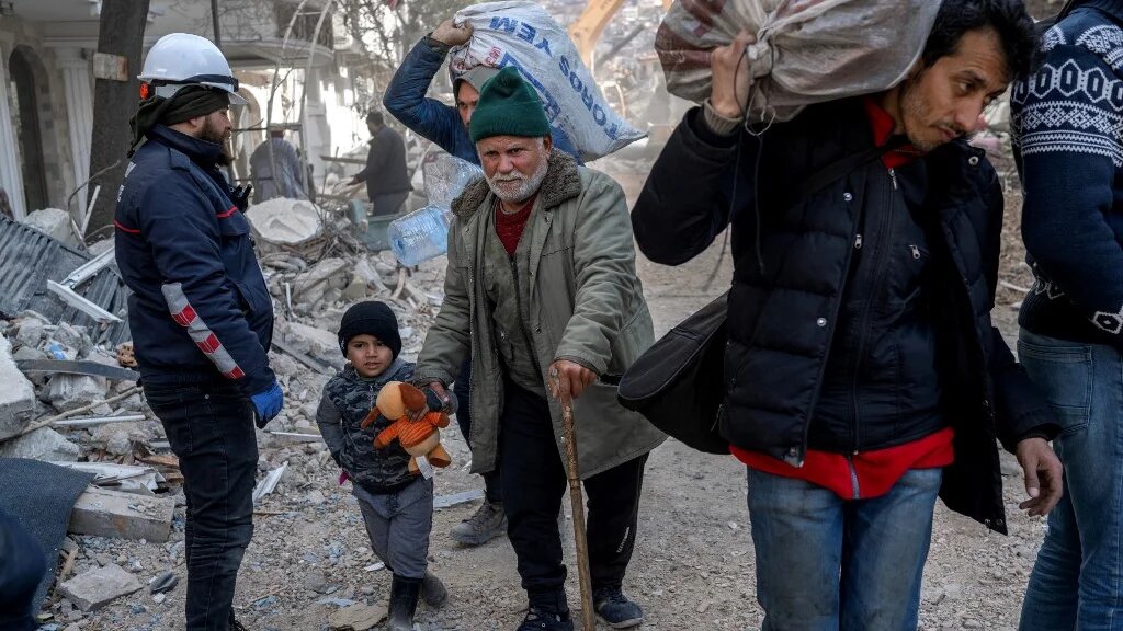 Un sinistré et son petit-fils marchent dans les décombres de la ville historique d’Antakia à Hatay en Turquie, le 11 février 2023 (AFP/Bulent Kiliç)