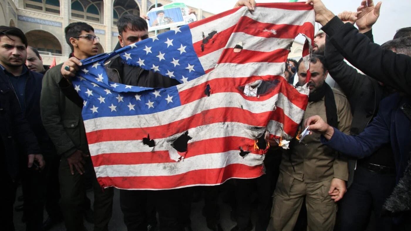 Des Iraniens détruisent un drapeau américain au cours d’une manifestation à Téhéran, en janvier 2020 (AFP)