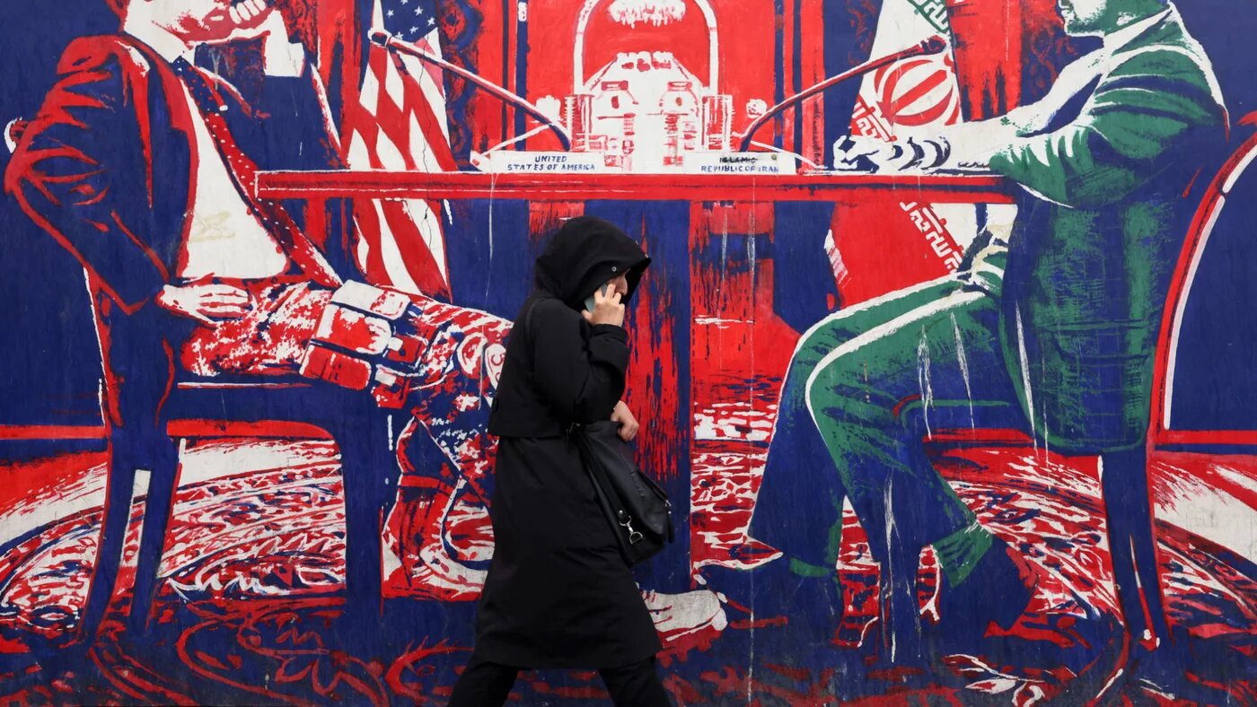 A woman walks past a mural painted on the outer wall of the former US Embassy in Tehran, dubbed the 'Den of Espionage', on 8 March 2025 (AFP)