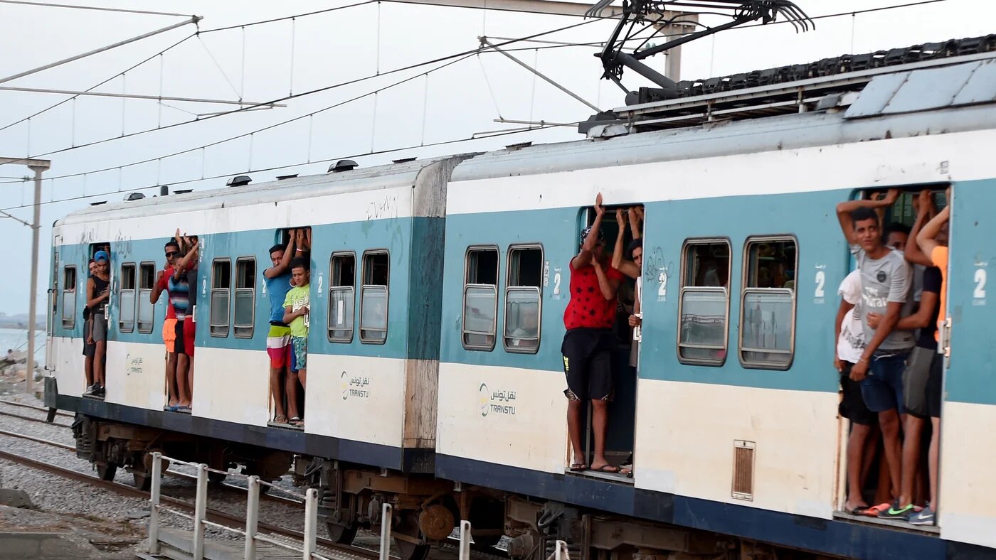 Tunisian youths look out of the doors of a train linking the port city of La Goulette with Tunis on the outskirts of the Tunisian capital on 12 July 2016.
