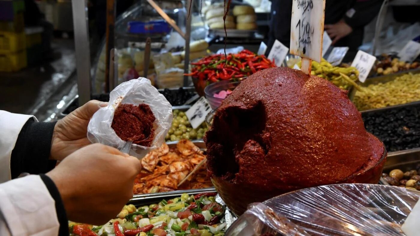 Un commerçant sert de la harissa à un client dans le marché central de la capitale Tunis le 1er décembre 2022 (AFP/Fethi Belaïd)