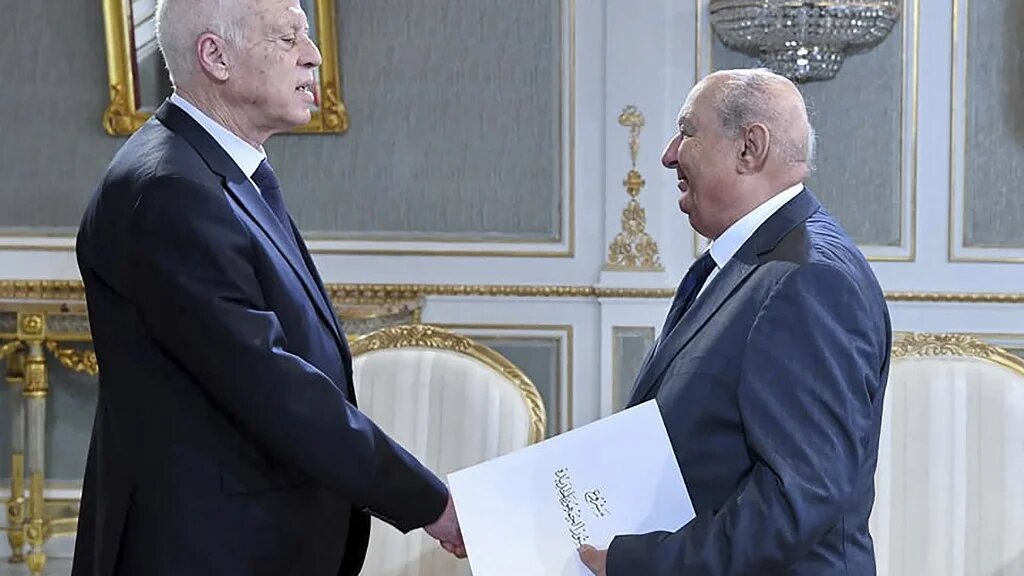 Le président de la Commission nationale consultative pour une nouvelle République, Sadok Belaïd, remet au président Kais Saied le projet de Constitution, le 20 juin 2022, à Tunis (AFP)