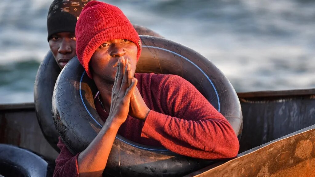 Des migrants d’Afrique subsaharienne sont assis dans un bateau de fortune utilisé pour se diriger clandestinement vers la côte italienne. Ils ont été retrouvés par les autorités tunisiennes au large de Sfax, le 4 octobre 2022 (AFP/Fethi Belaïd)