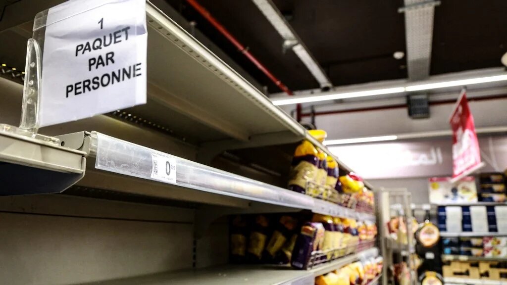 Une pancarte est placée sur des étagères presque vides de pain et d’autres produits alimentaires à base de blé indiquant en français « un sac par personne », dans un supermarché de Tunis, le 13 mars 2022 (AFP/Anis Mili)