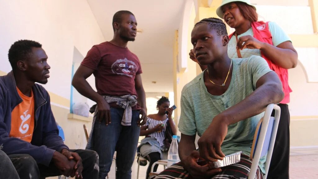 Un membre du Croissant-Rouge tunisien s’adresse aux migrants qui ont fui les violences à Sfax vers la zone tampon militarisée entre la Tunisie et la Libye, le 12 juillet 2023 (AFP/Fathi Nasri)