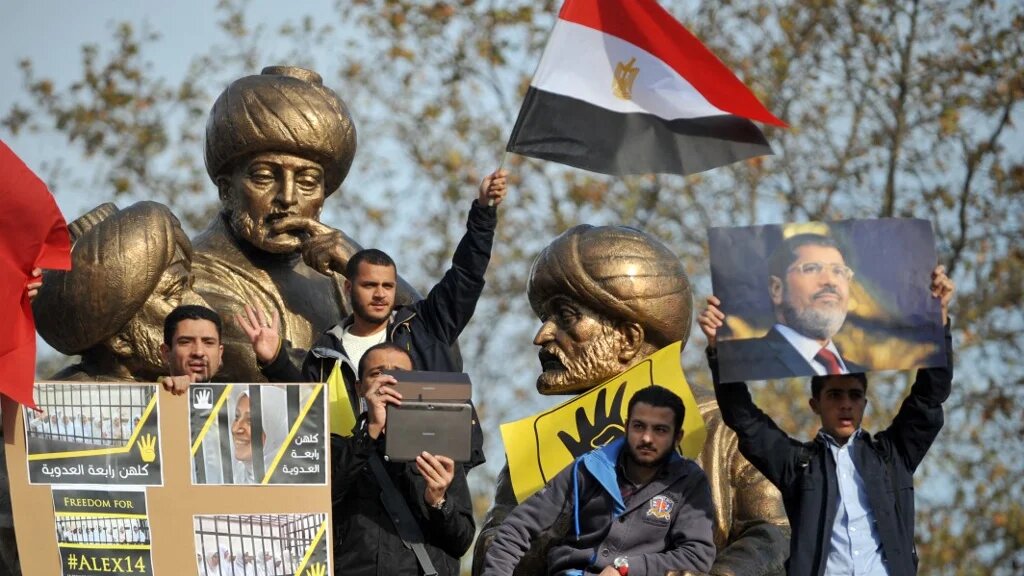 Protesters flash the four-finger sign and hold a picture of late Egyptian President Mohamed Morsi on 29 November, 2013 during a pro-Morsi rally in Istanbul (AFP)