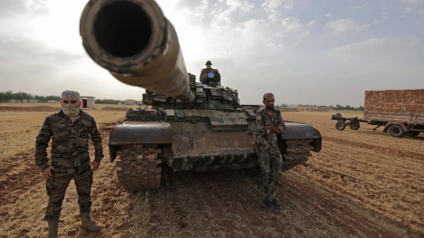  Des combattants syriens, soutenus par la Turquie, autour d’un char lors d’un exercice militaire dans la campagne de Manbij, en Syrie, le 2 juin 2022 (AFP)