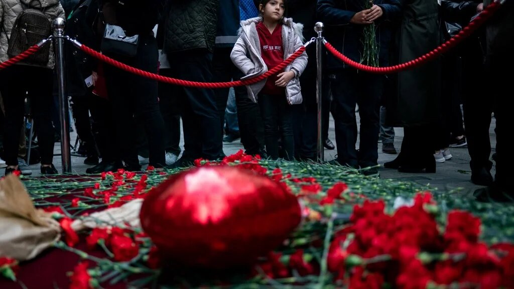 Une jeune fille regarde les gens pleurer les victimes de l’explosion du 13 novembre dans la rue commerçante animée d’Istiklal à Istanbul le 14 novembre 2022 (AFP/Yasin Akgul)