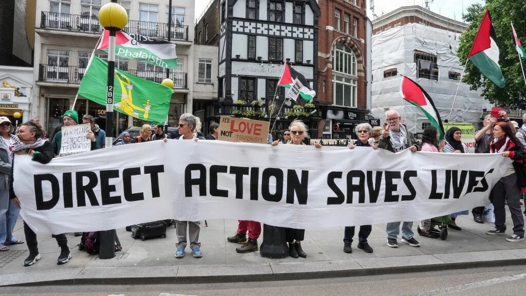 Protesters hold a banner outside the Royal Courts of Justice in central London on 15 June 2026, amid a legal standoff between the government and Palestine Action (Carlos Jasso/AFP)