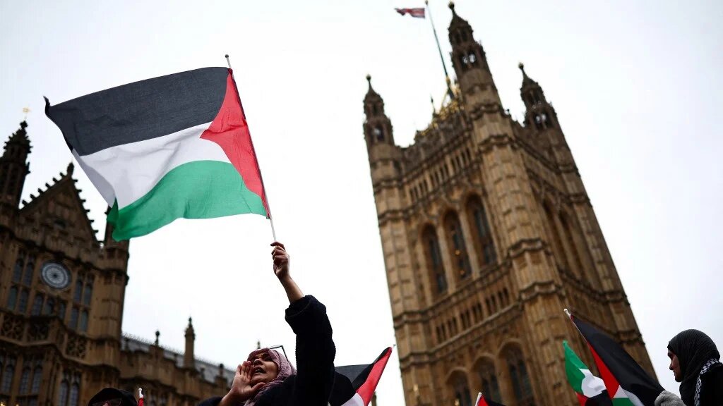 A demonstrator waves a Palestinian flag during a protest in London’s Parliament Square on 21 February 2024 (Henry Nicholls/AFP)