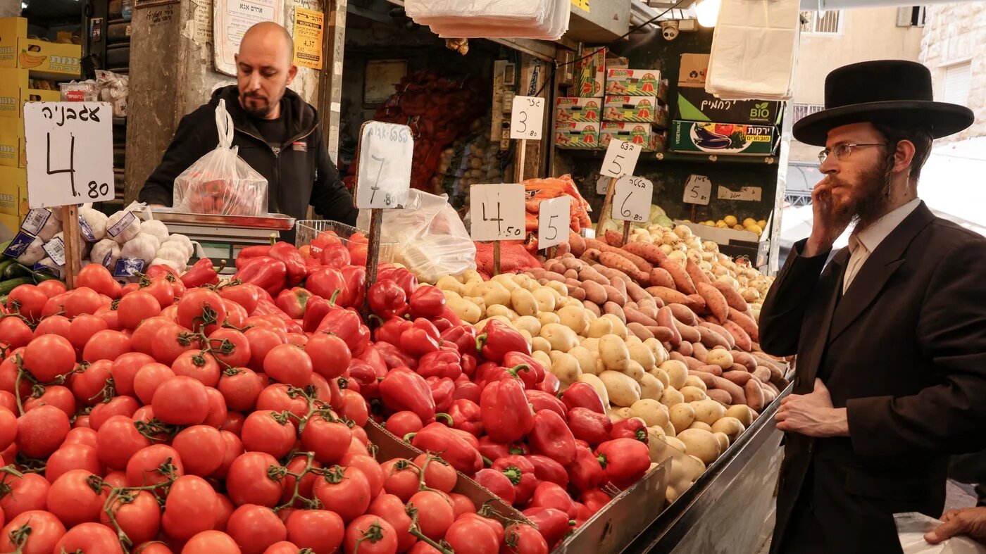 An ultra-Orthodox jewish stands infront of a vegetable vendor's stand at the Mahane Yehuda market before the start of Shabat, in Jerusalem on 31 January, 2025 (Hazem Bader/AFP)