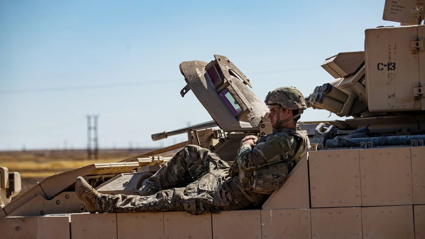 A US soldier rests on a tank as troops patrol oil fields near Syria's northeastern border with Turkey on 3 September 2024 (Delil Souleiman/AFP)