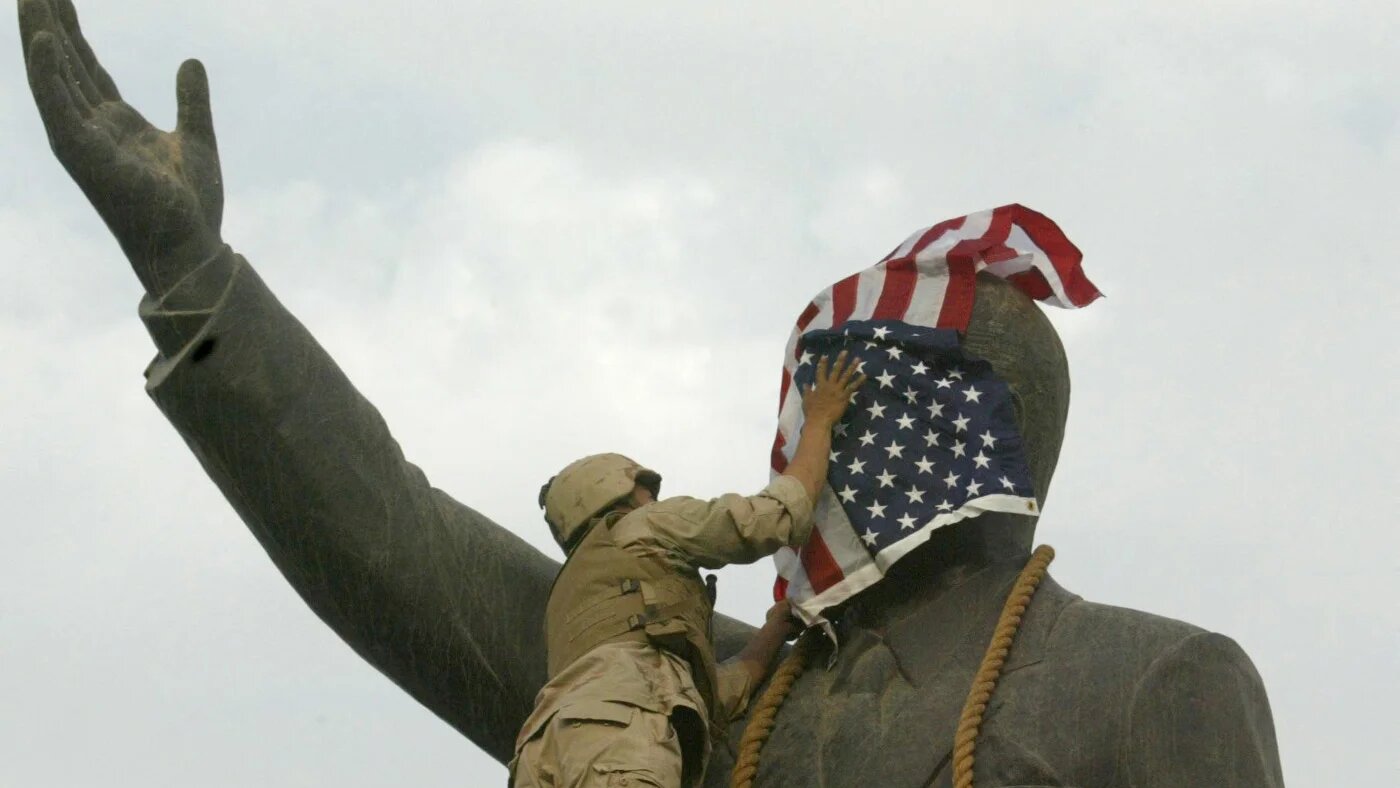 A US Marine covers the face of Iraqi President Saddam Hussein's statue with the US flag in Baghdad's al-Firdos Square on 9 April 2003 (AFP)