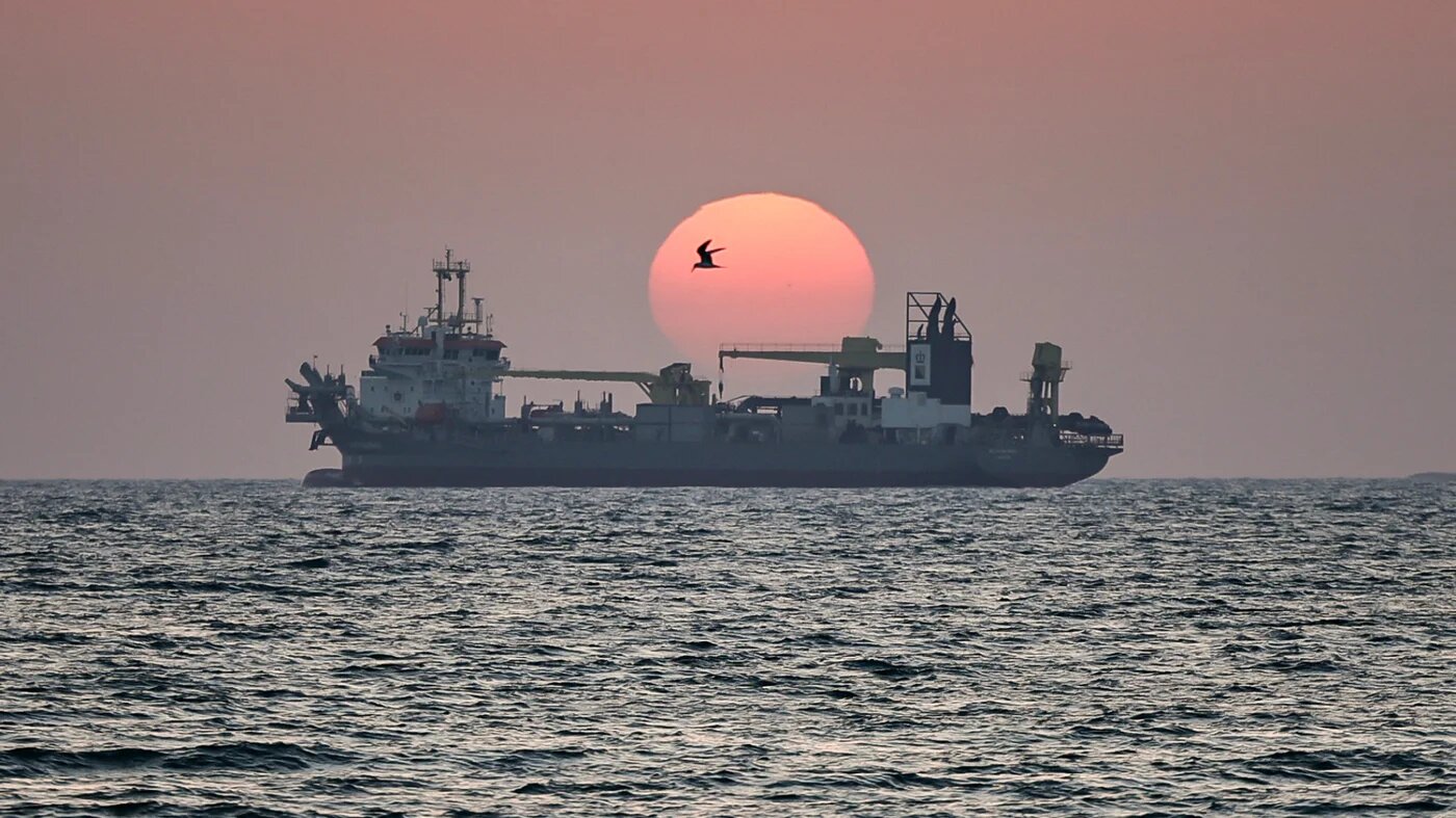 The sun sets over a vessel off the coast of Dubai on 2 June 2026 (AFP)