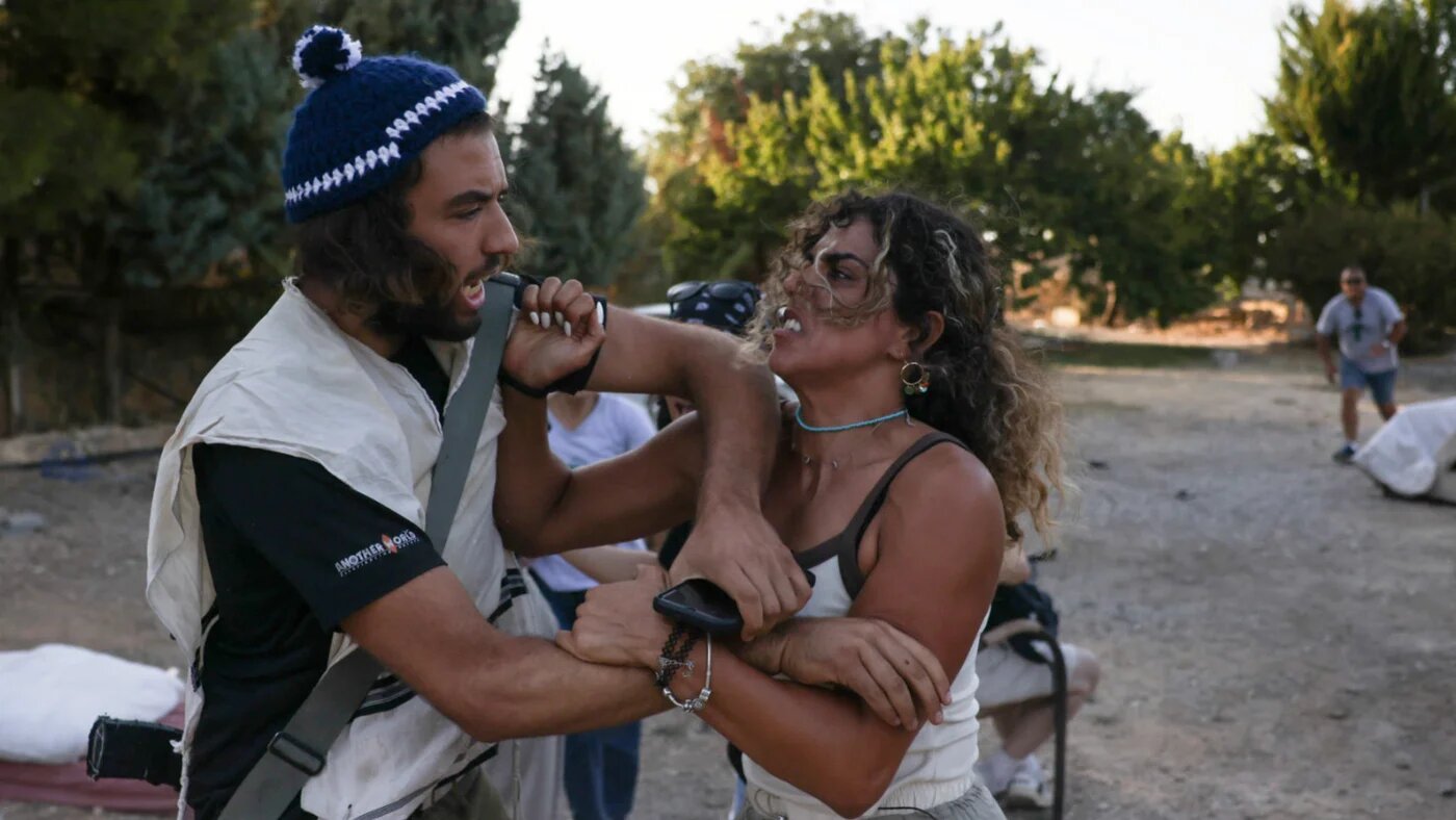 Palestinian Alice Kisiya (right), whose family land was taken over by armed Israeli settlers planning to build a new outpost, confronts a settler in al-Makhrour, occupied West Bank, on 22 August 2024 (AFP)