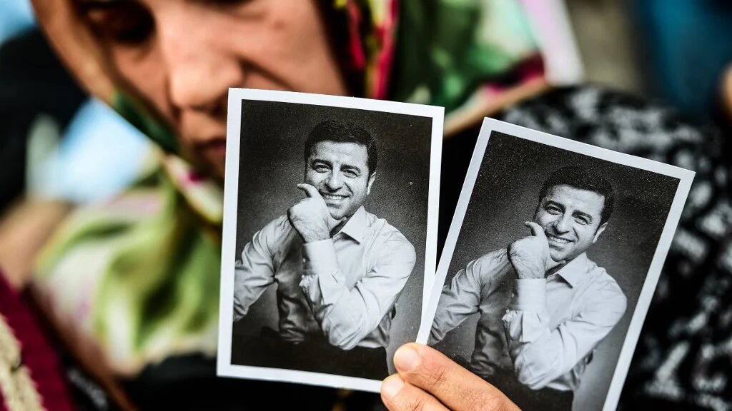 A woman holds pictures of former leader of the pro-Kurdish Peoples' Democratic Party HDP Selahattin Demirtas, in jail for a year and a half, and HDP candidate for the upcoming presidential election, during a rally on May 4, 2018 in Besiktas district of Istanbul. (AFP)