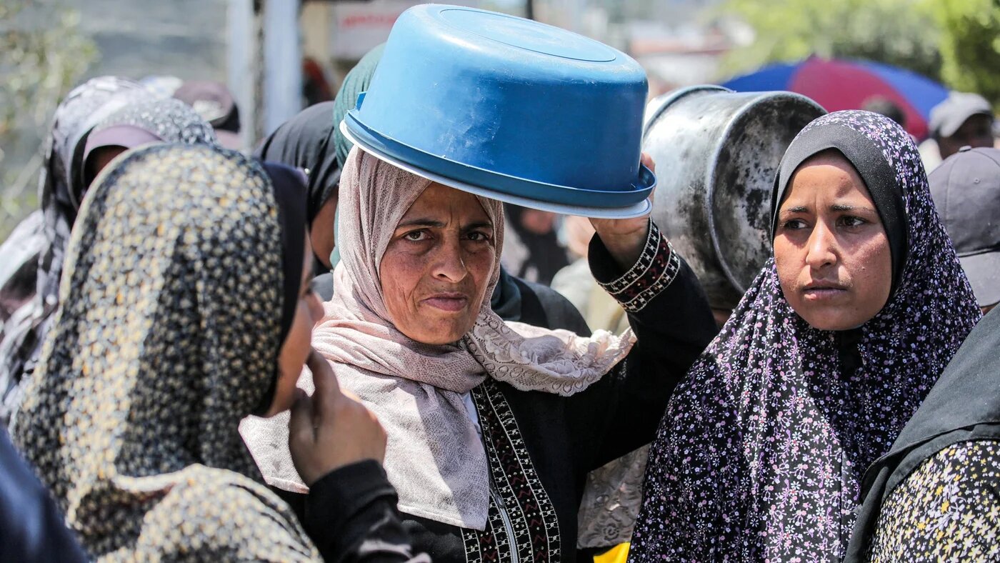 Women queue to receive food rations from a public kitchen in Deir al-Balah in the central Gaza Strip on 13 May 2024 (AFP)