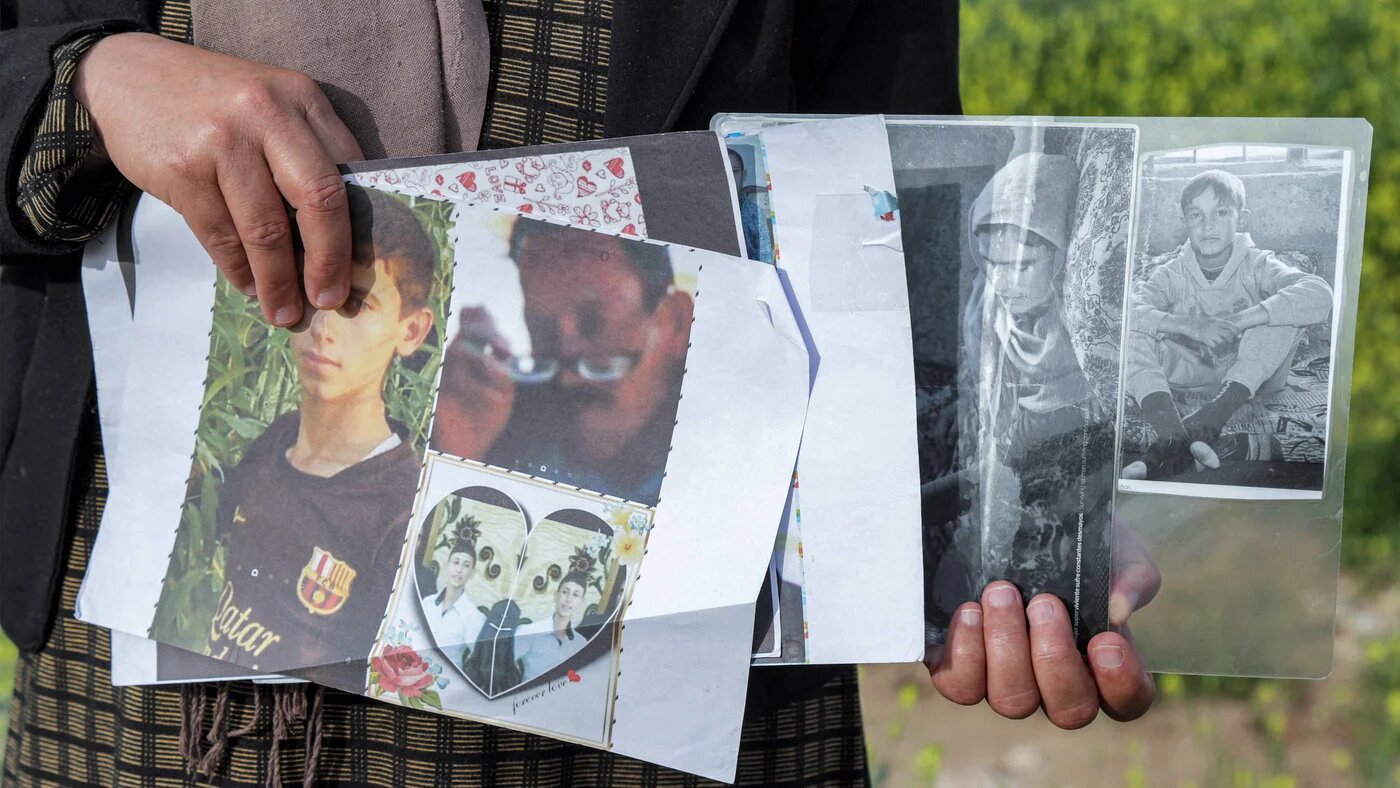 A displaced Yazidi woman holds photos of family members kidnapped by the Islamic State group in the Sharya region, some 15 km near the northern Iraqi city of Dohuk, 19 April 2023 (Safin Hamid/AFP)