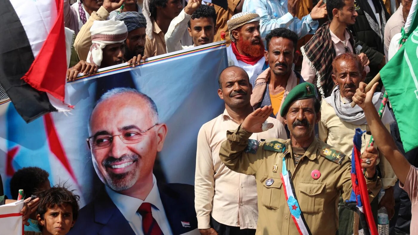 Supporters of the UAE-backed Southern Transitional Council hold an image of the STC leader Aidarous Al-Zubaidi as they wave the old South Yemen flag, in Aden, on 14 December 2025 (Saleh al-Obeidi/AFP)