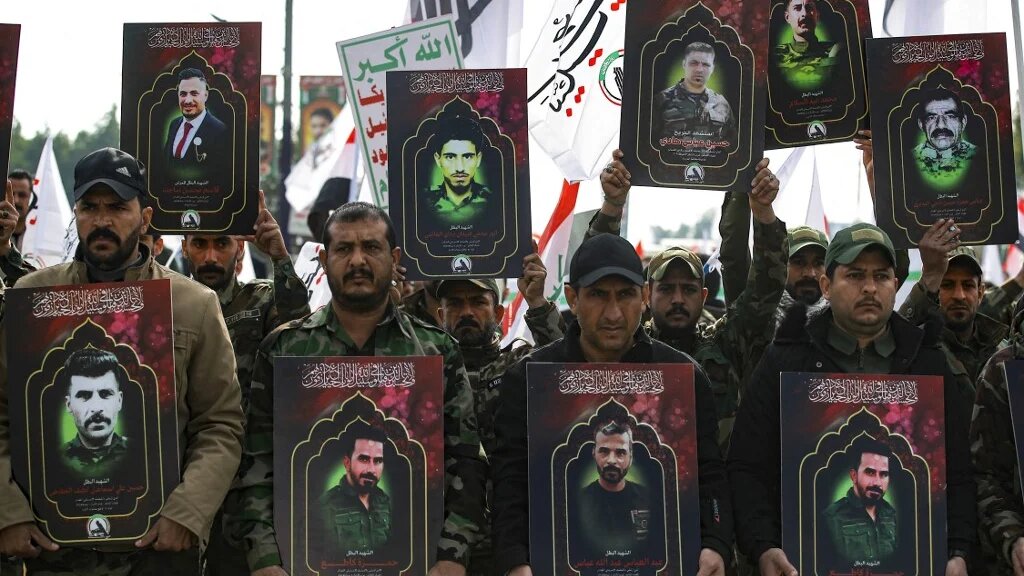 Des membres des forces paramilitaires irakiennes du Hachd al-Chaabi portent des portraits de personnes tuées lors de frappes américaines dans l’ouest de l’Irak, avant leurs funérailles à Bagdad le 4 janvier 2024 (AFP/Ahmad al-Rubaye)