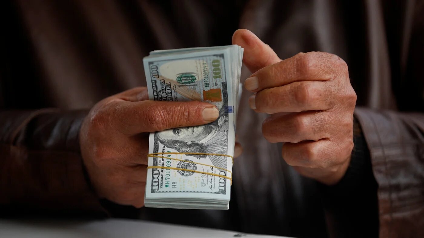 A man counts US dollar banknotes at al-Kifah stock market in Baghdad on 27 December 2022 (Ahmad al-Rubaye/AFP)