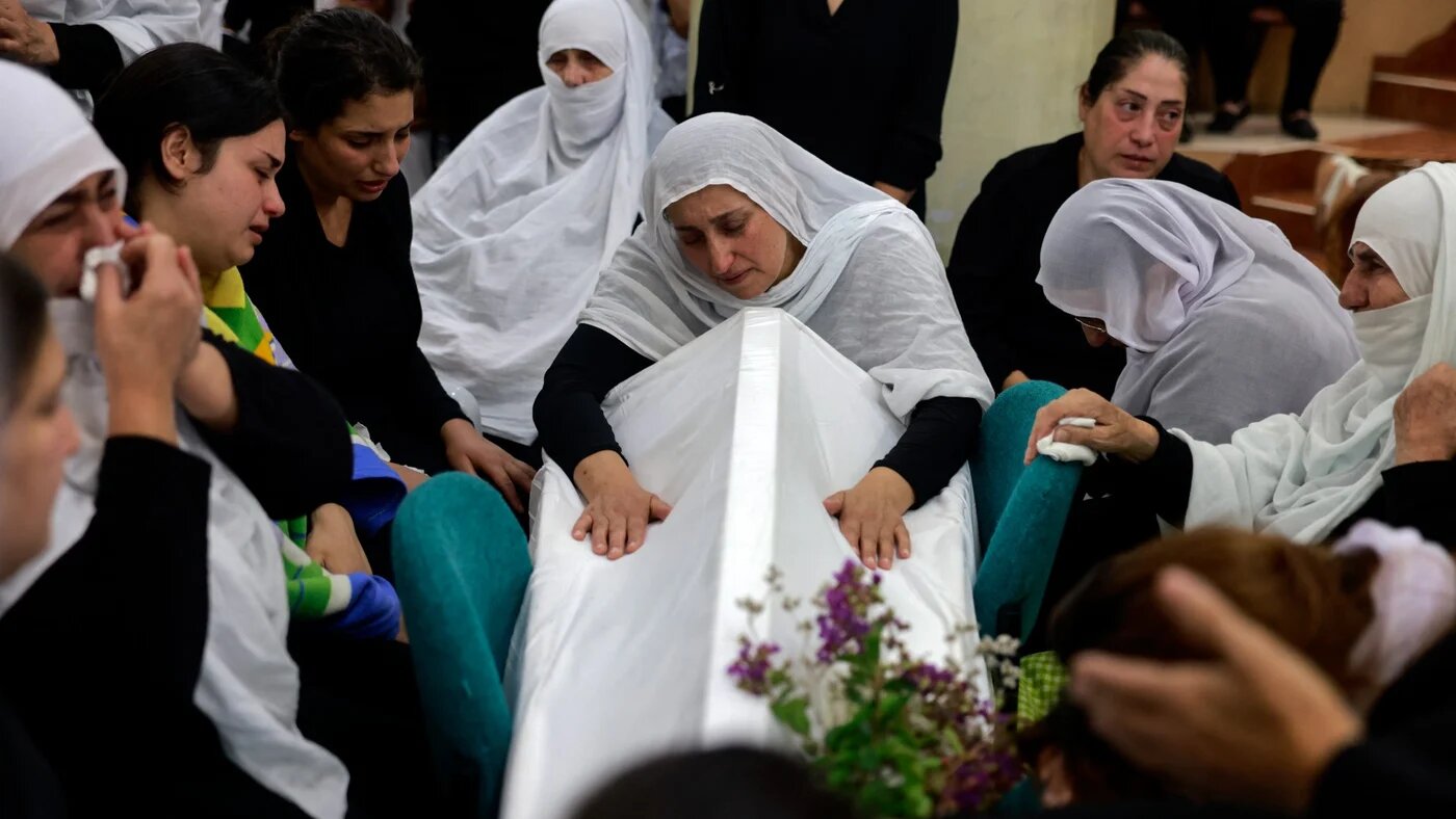 Women mourn by a coffin during a funeral in the occupied Syrian Druze town of Majdal Shams in the occupied Golan Heights on 28 July 2024 (AFP/Menahem Kahana)
