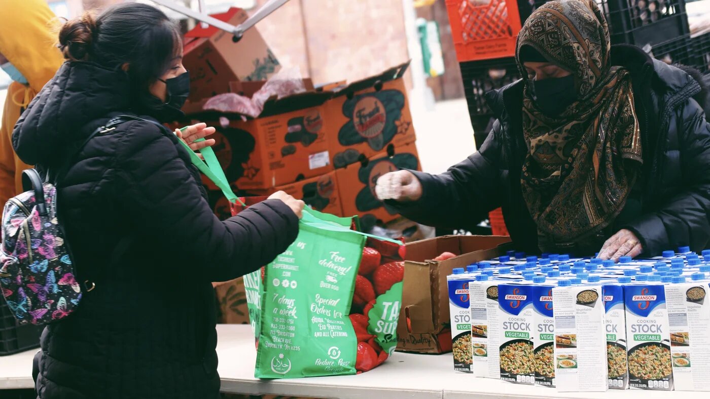 A volunteer handing out food items to a person who accesses the pantry in Brooklyn.